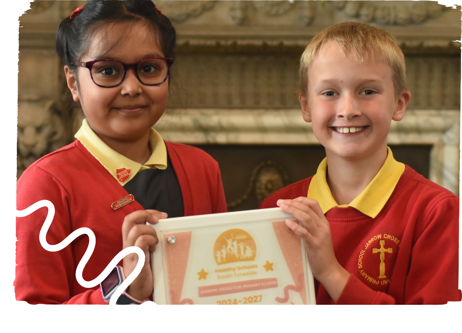 Young boy and girl from Jarrow Cross CofE Primary School holding the Healthy Schools South Tyneside award their school received for 2024 - 2027